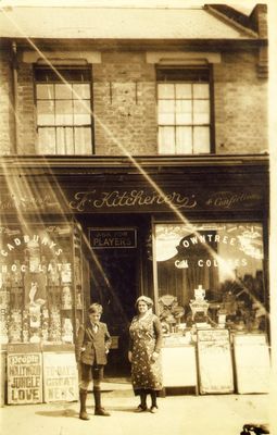 F. Kitchener, tobacconist and confectioner
Location and date unkown. This is not Kitchener's fruit and vegetable shop at 103 Chase Side. The right-hand window has a display of confectionary, with "Terry's All Nut Assortment" for 2/- and indivdual "Toffles" for 2d each. The left-hand window is full of cigarettes, with, e.g. Player's Navy Cut at 25 for 1/3d., 50 for 2/3d. and 100 for 4/6d. "Star" cigarettes are sold in quantities of 5 for 2d., 10 for 4d. and 20 for 8d.
Keywords: shops;pillars