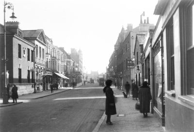 Church Street, looking west
The building with the triangular pediment on the left is the post office, opened in 1906. The projecting sign on the right reads "W. WELCH / REPAIRS / GARAGE". (The last horse cab, a four-wheeler owned by W. Welch, ceased plying for hire at Enfield Chase station in April 1929. - [i]History of Enfield[/i], vol.3, p.238.)
Keywords: roads and streets;post offices;garages