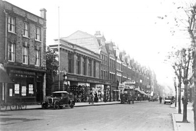 Church Street, looking west
The first building on the left has the signboard "JAMES NEILSON", and the next, lower one is "PEARSON BROS." The gable end in the distance has the sign "THE RISING SUN".
Keywords: shops;roads and streets;cars