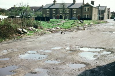 Gordon Road and Halifax Road
Slide has note which appears to read "Off Gordon Lane".  Gordon Lane is the previous name of the east end of Gordon Road, where it meets Baker Street. 
[i]Comment from Daren Gordelier, 2014-02-16: "This piece of unmade road, was probably developed in the 1970's. No 101 Gordon Road stands to the fore, and behind on the grass area flats were built 88-110 Halifax Road. A pathway through on the right of this picture remains leading to Halifax Road, the houses seen here are nos. 79-87 Halifax Road, Bellamy Road is on the right that then links to Manor Road."[/i]
Keywords: roads and streets;houses
