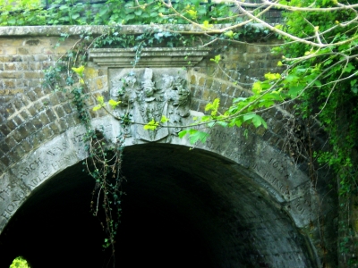 Clarendon Arch, Bush Hill
Bult in 1786, the arch ring of Portland stone bears a fine shield of arms with mantling helm and the crest of Myddelton, and the inscription "This arch is at the end of a long, barrel-vaulted brick tunnel which carries the Salmons Brook beneath the New River". Above the north-west side of the tunnel is a stone with the inscription: "This bank of earth was raised and formed to support the Channel of the New River. And the frame of timber and lead which served that purpose 173 years was removed and taken away. MDCCLXXXVI Peter Holford, Esquire, Governor". - [i]Treasures of Enfield[/i], p.119.
Keywords: New River;rivers and streams;Grade II listed;tunnels
