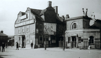 Greyhound Inn and vestry offices
The Greyhound Inn has a sign with an illegible name, below which is "PHOTOGRAPHER PICTURE FRAME MAKER". There is a poster for The Bohemian Girl on the east wall. The inn was demolished when Barclays bank was built on the site in 1897.
Keywords: 1890s;pubs